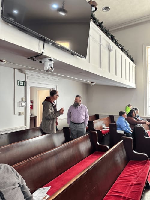 People greeting one another in the First Baptist Church sanctuary